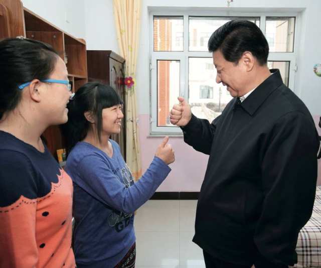 2014 年1月28日，习近平在呼和浩特市儿童福利院宿舍向聋哑女孩王雅妮（左二） 和放假“回家”的大学生闫志净学习哑语“谢谢”&nbsp;&nbsp;&nbsp; 兰红光摄/本刊